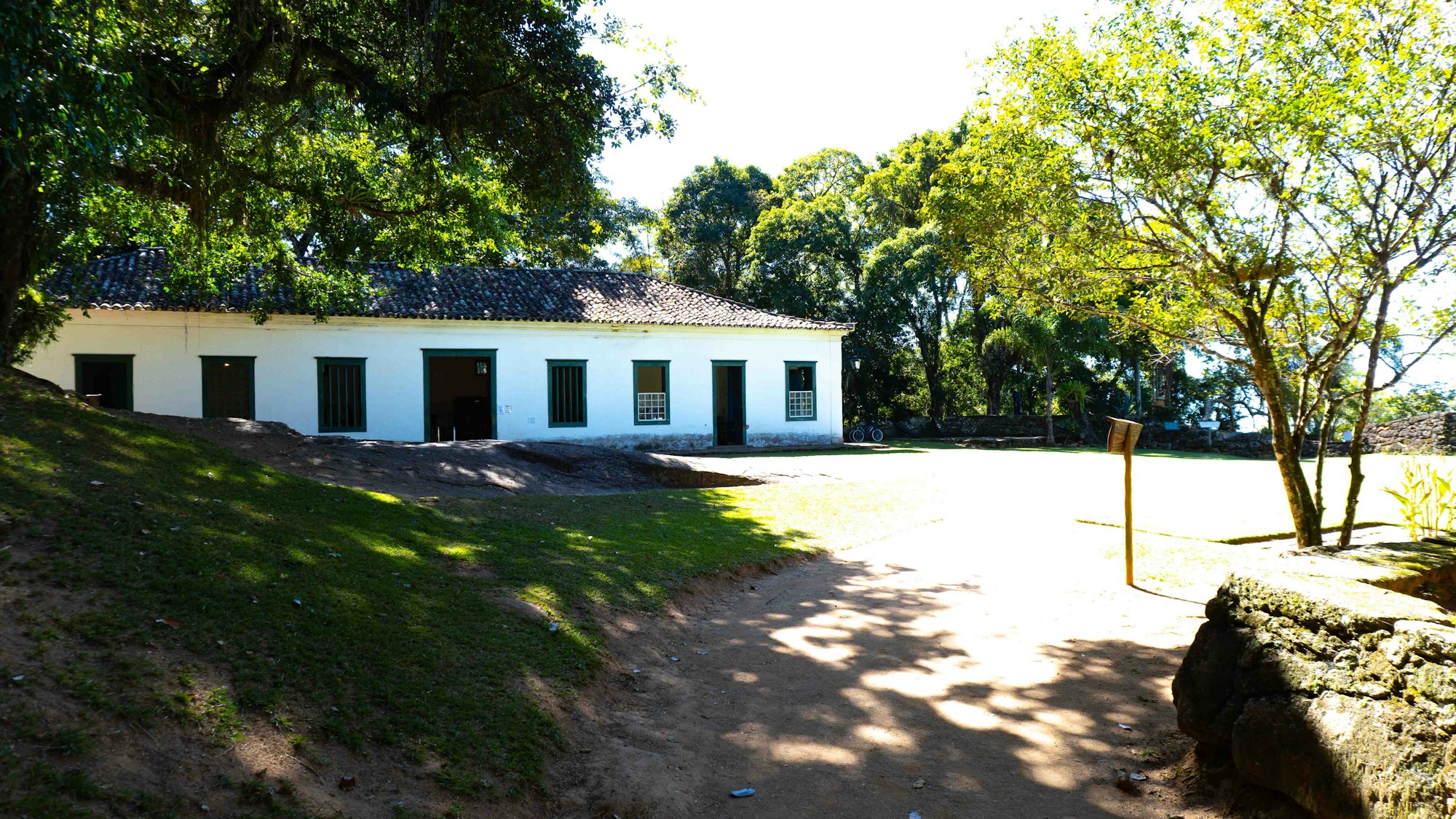 A white colonial building with green shutters beside a grass courtyard