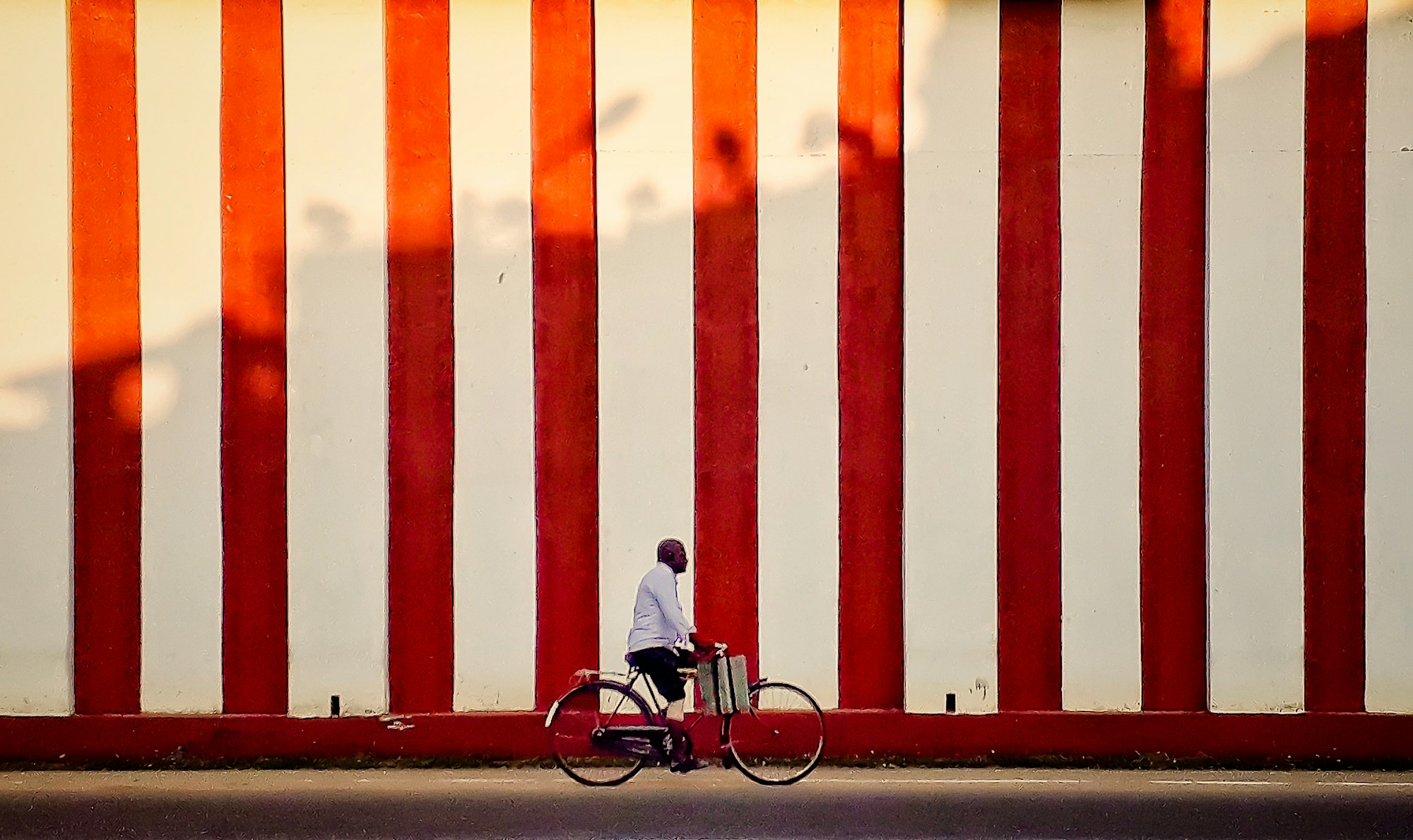 A cyclist beside the red and white striped wall of a northern temple