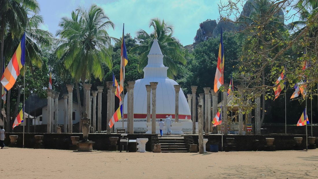 A white stupa and standing stone pillars among the ruins at Polonnaruwa